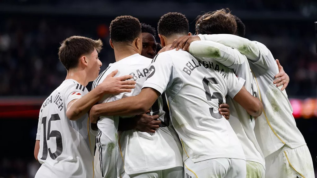Real Madrid players celebrating together on the pitch under the stadium lights